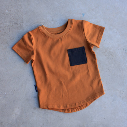 brown t-shirt with a black pocket on a gray surface