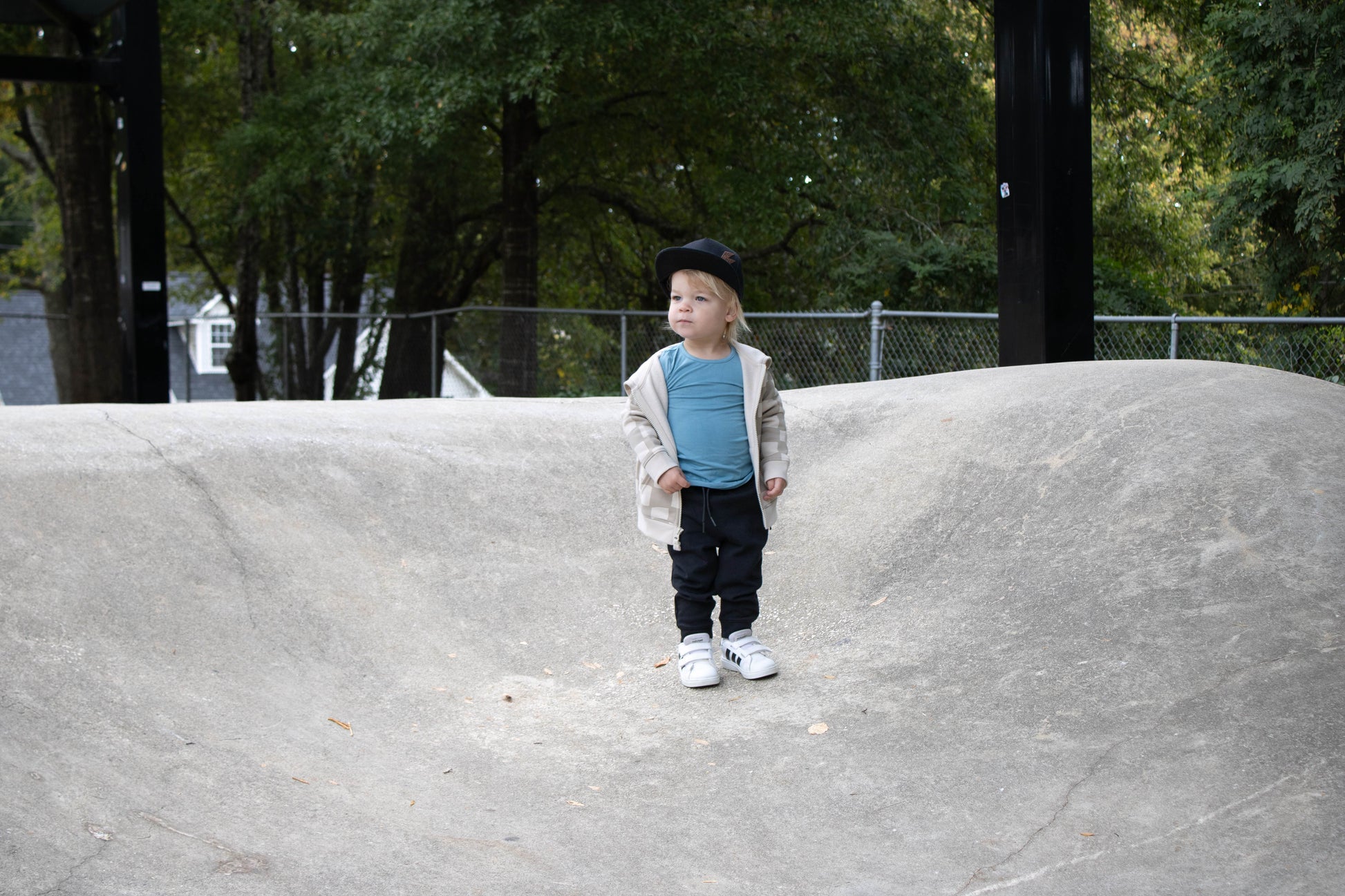 Child standing on a concrete ledge with trees in the background