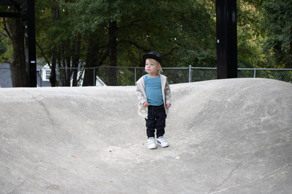 Child standing on a concrete ledge with trees in the background