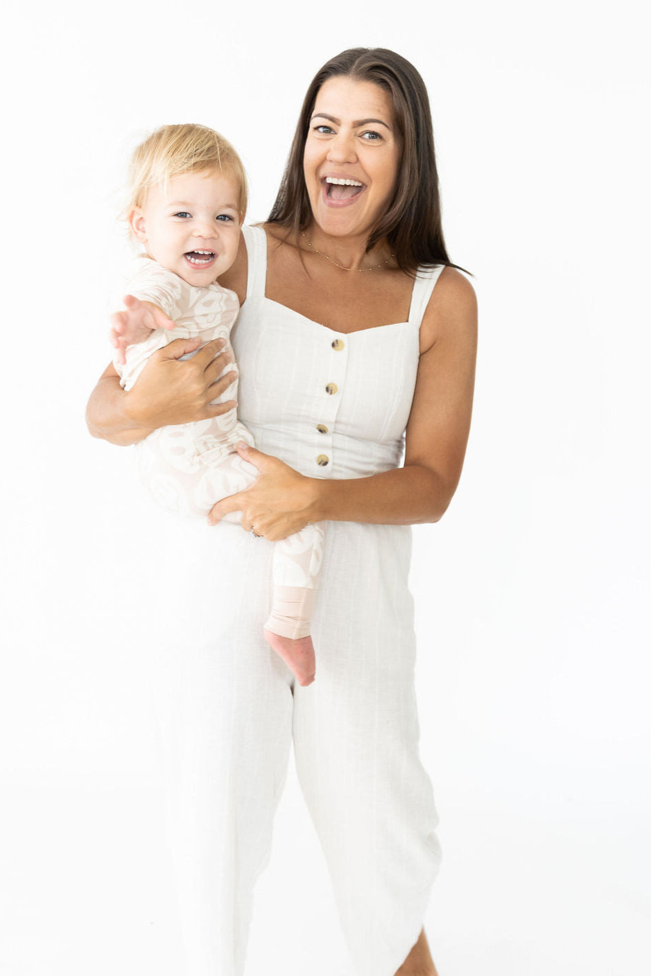 Woman in a white outfit holding a baby on a white background