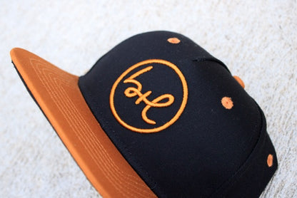 Black and brown cap with a logo on a textured surface