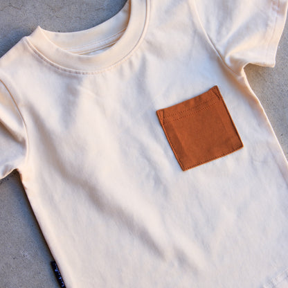 White t-shirt with a brown pocket on a gray surface