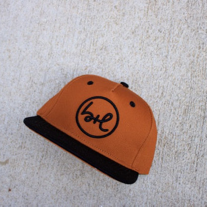 brown and black cap with a logo on a textured surface