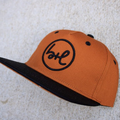 brown and black cap with a logo on a textured surface