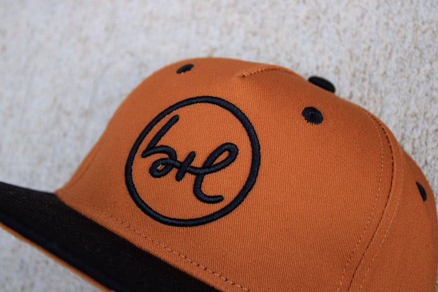 Brown cap with black logo on a textured surface
