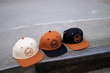 Three caps with a logo on a concrete surface