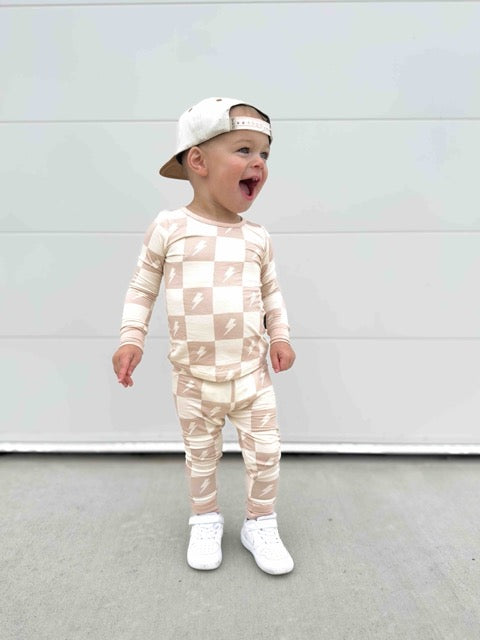 Child wearing a checkered outfit with lightning bolt patterns against a plain background